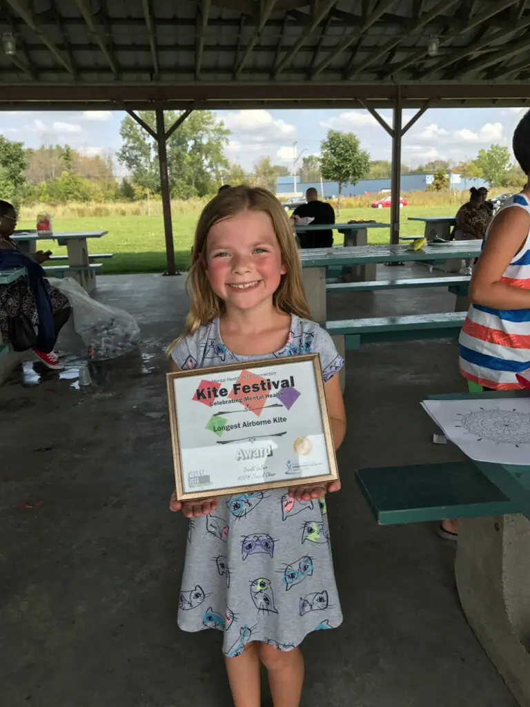 Young girl holding a "longest airborne kite" award at the kite festival