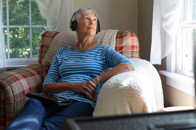 Woman sitting in a chair with headphones on looking out a window
