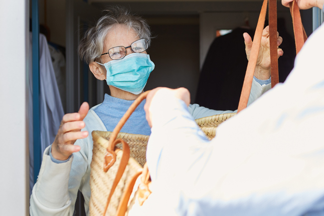 Woman with face mask on accepting bag from delivery person